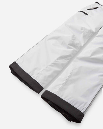 Detail view of the lower legs on the pristine white Reima Terrie kids' ski pants, emphasizing the rugged black reinforced hems designed to protect against sharp ski edges.