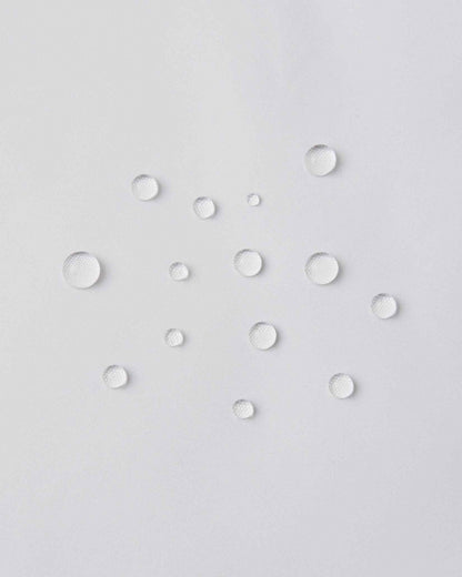 Macro close-up of water droplets actively beading and rolling off the pristine white outer shell of the Reima Terrie kids' ski pants, visually highlighting the high-performance breathable and waterproof Reimatec technology.