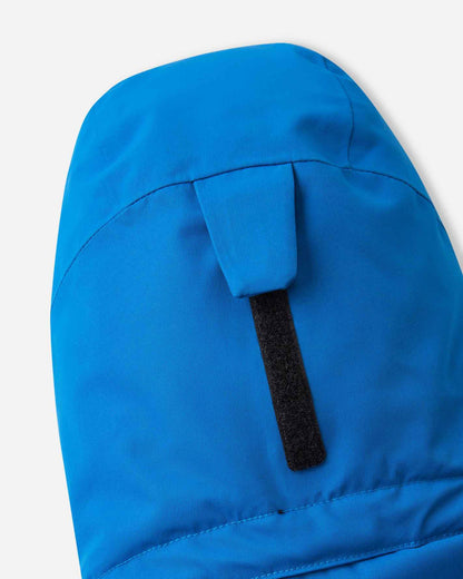 Macro view of the back of the hood on the bright blue Reima Tieten children's winter gear, focusing on the hook-and-loop velcro strap that allows for a customized fit over safety helmets.