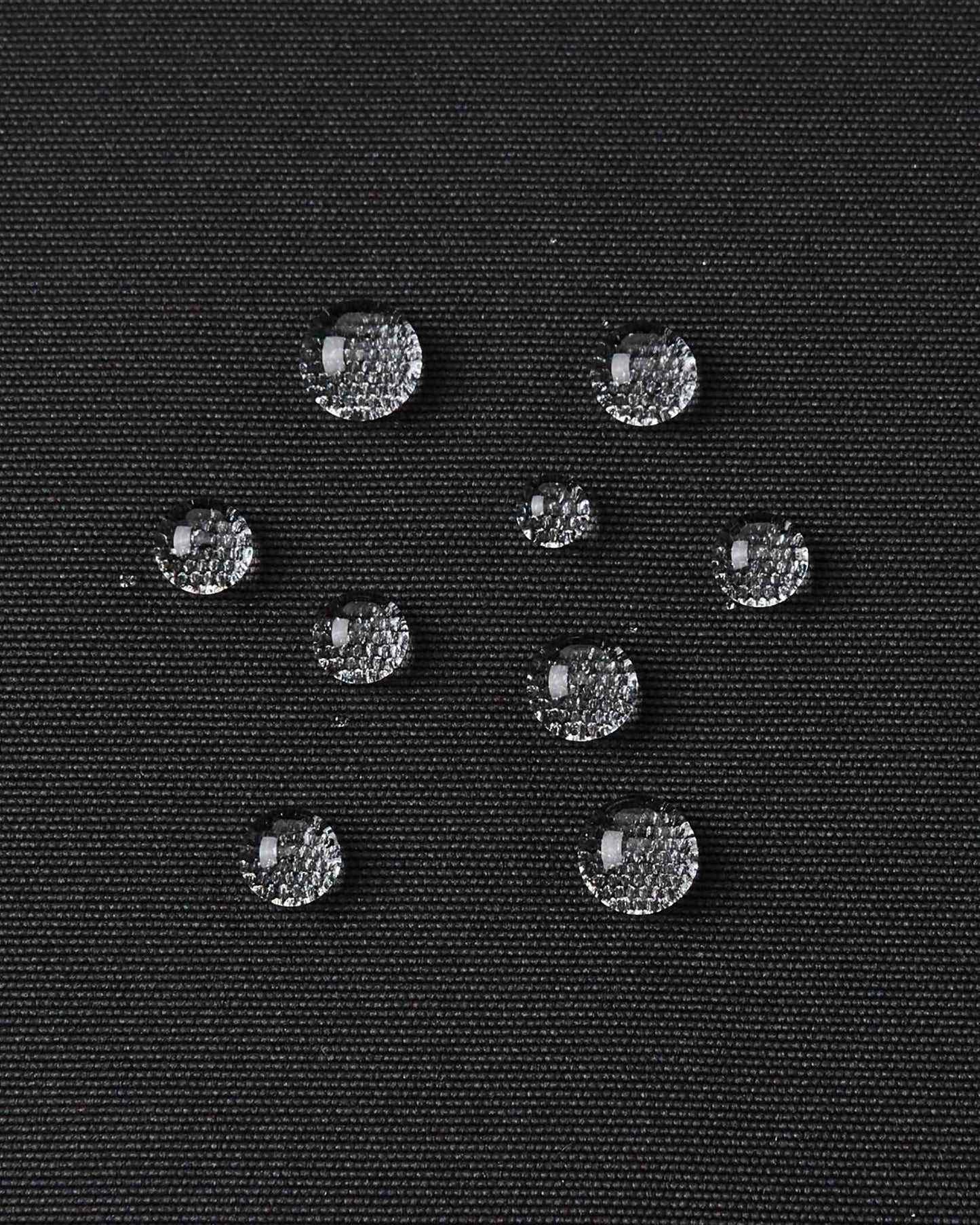 Water droplets bead up on the black outer material of the kids Reima Tieten ski jacket to show its waterproof finish.