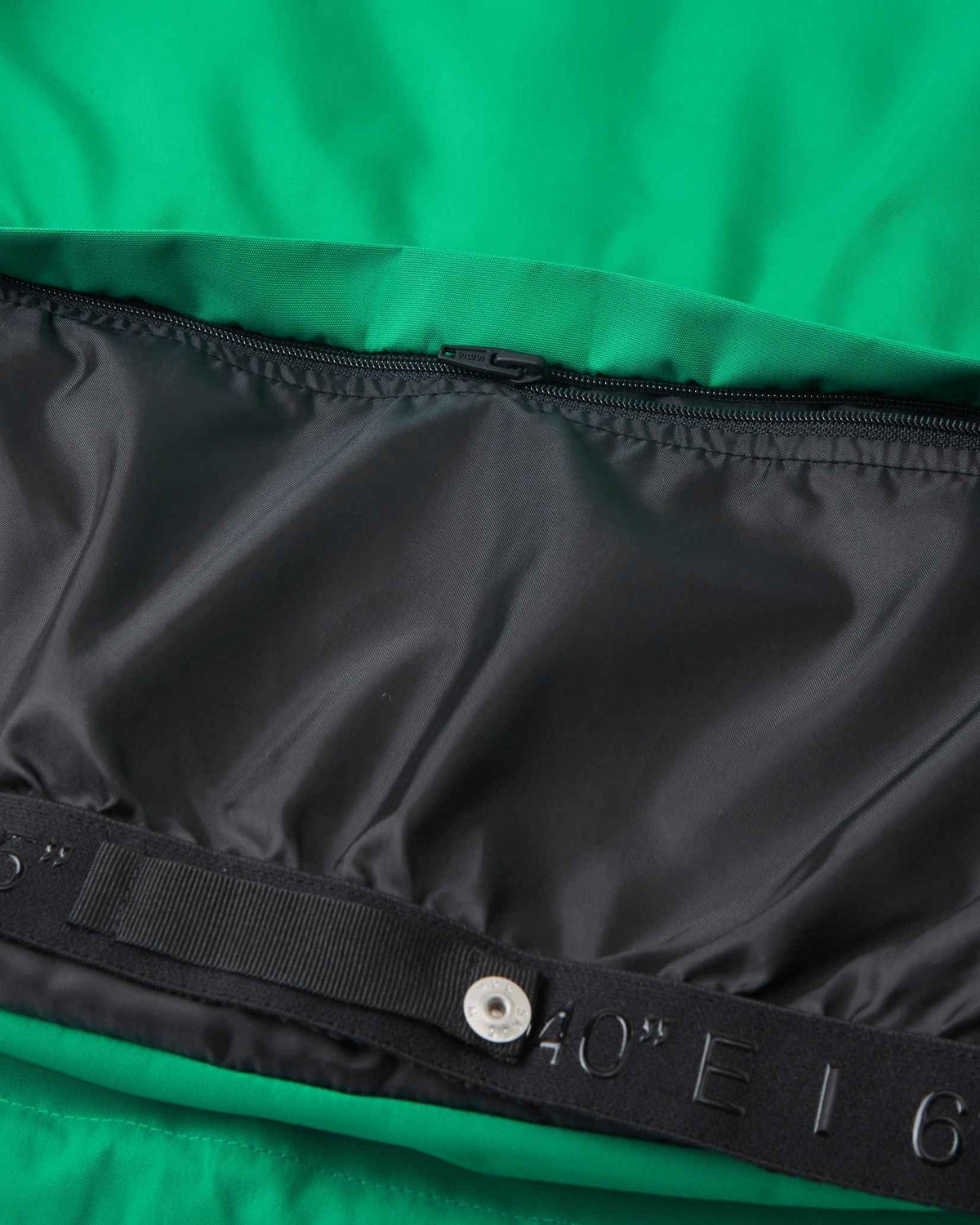 Macro close-up of the internal waist gaiter zipper track on the green Reima Tieten kids' weatherproof jacket, demonstrating the robust attachment points for ultimate winter weather defense.