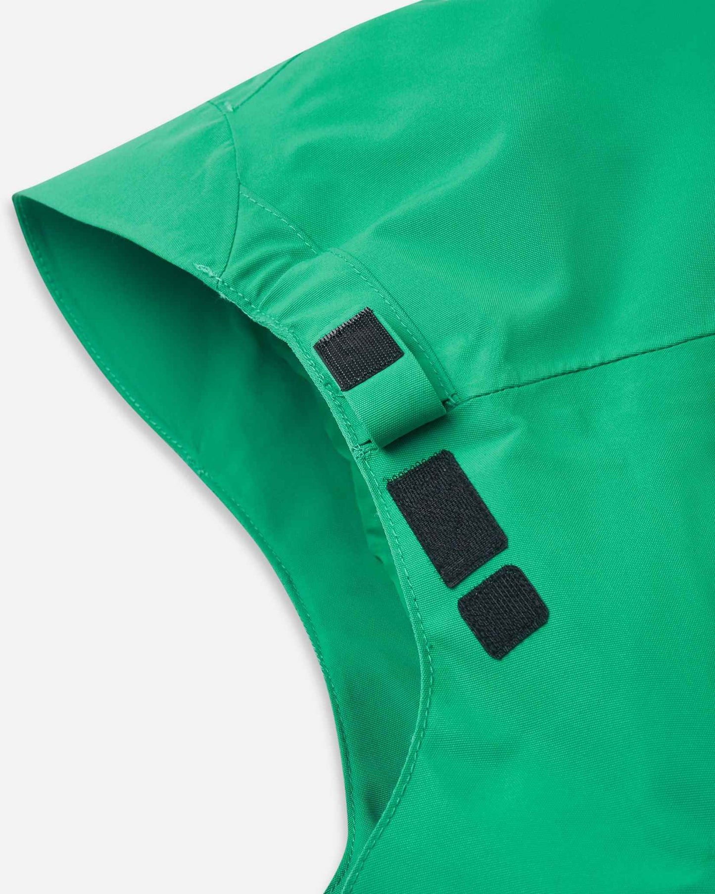 The side of the green Reima Tieten ski jacket hood shows a black velcro adjustment strap.