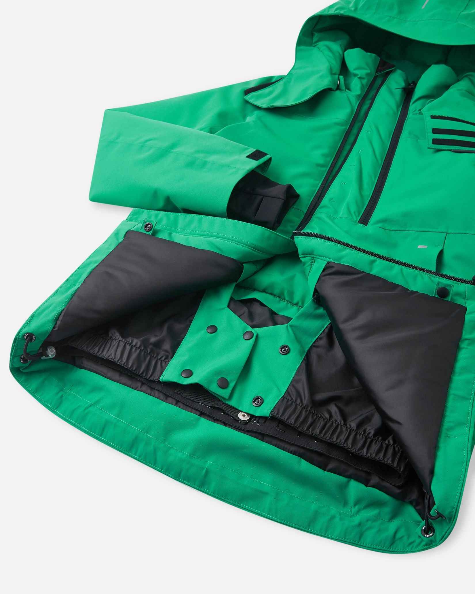 The inside of the green kids ski jacket reveals a black zippered chest pocket above a larger mesh storage pouch.