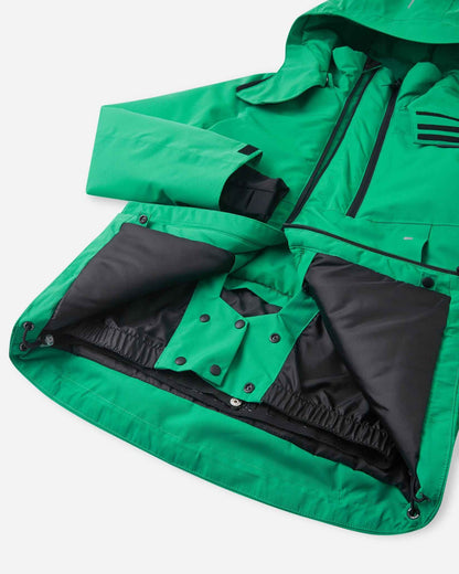 The inside of the green kids ski jacket reveals a black zippered chest pocket above a larger mesh storage pouch.