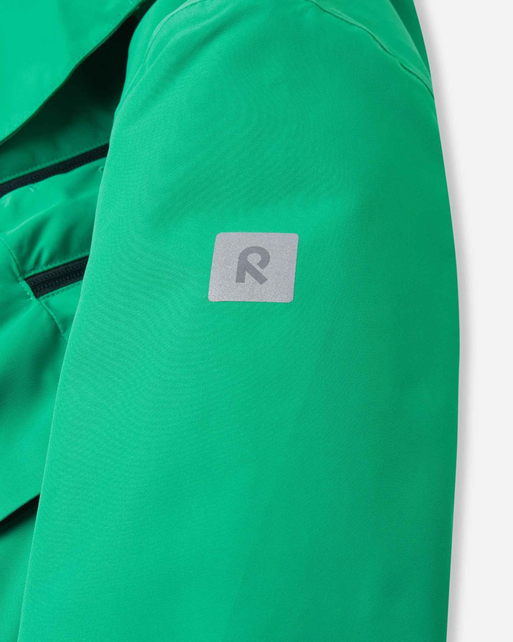 A small reflective Reima logo sits on the upper arm of the green kids winter coat.