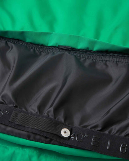 Snap buttons attach the black inner snow skirt inside the bright green kids ski coat.