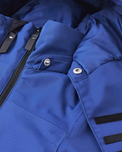 The top collar of the blue winter jacket sits open to reveal metal snap buttons and a dark interior lining.