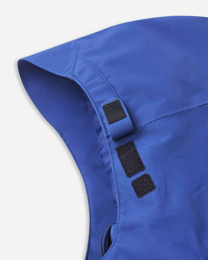 A dark strap rests on the side of the blue jacket hood for quick size adjustments.