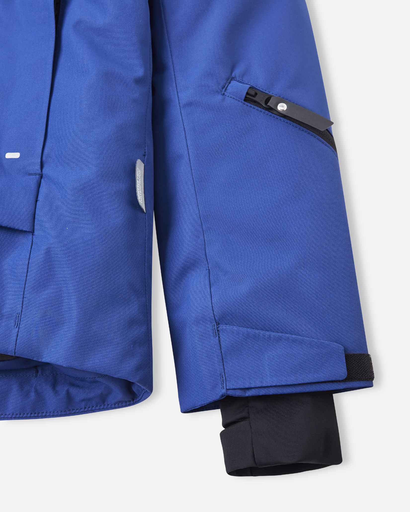 An internal black protective snow skirt sits near the bottom hem of the blue winter jacket.