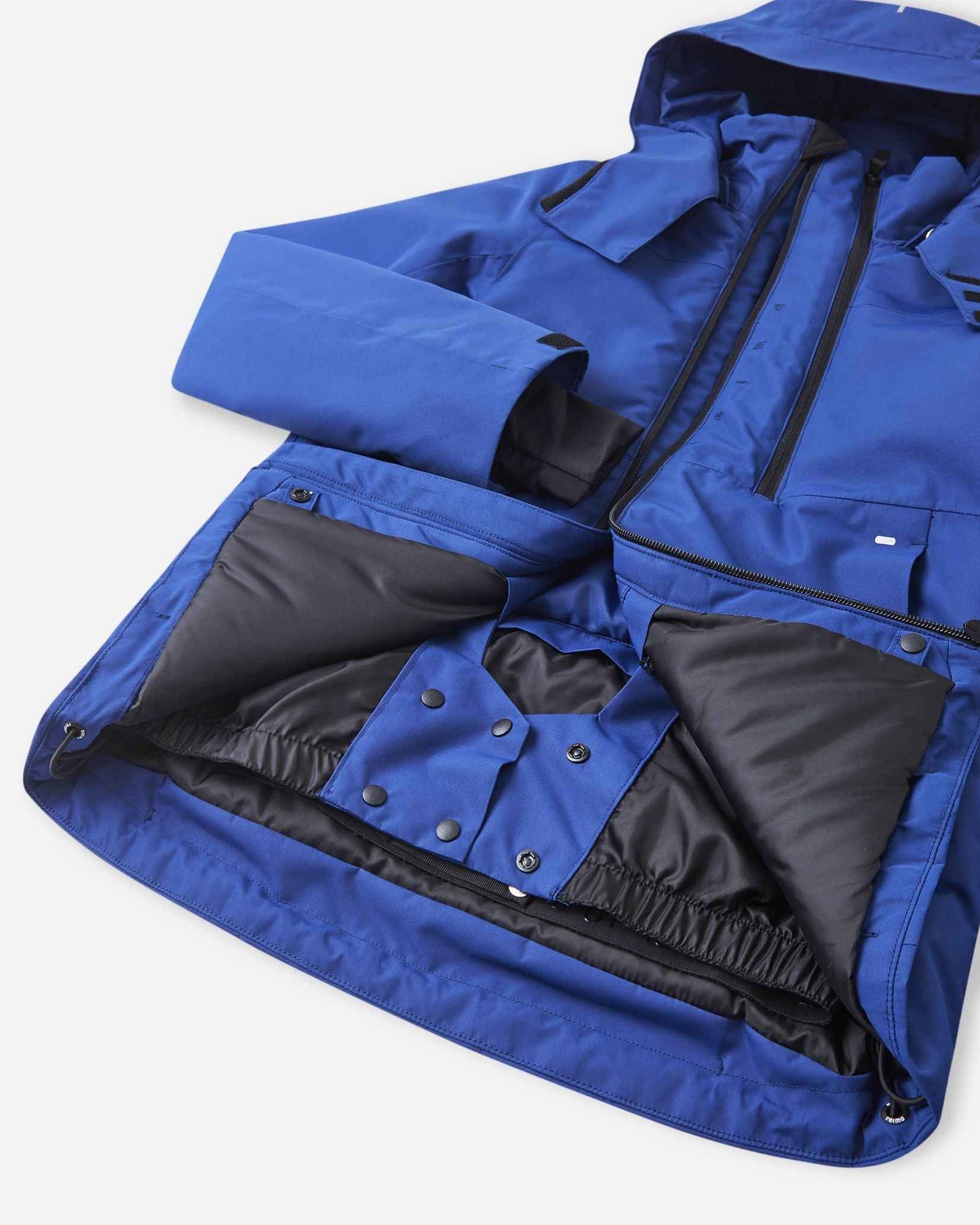 An open blue winter jacket displays an internal black zip pocket sitting next to a stretch mesh goggle pocket.