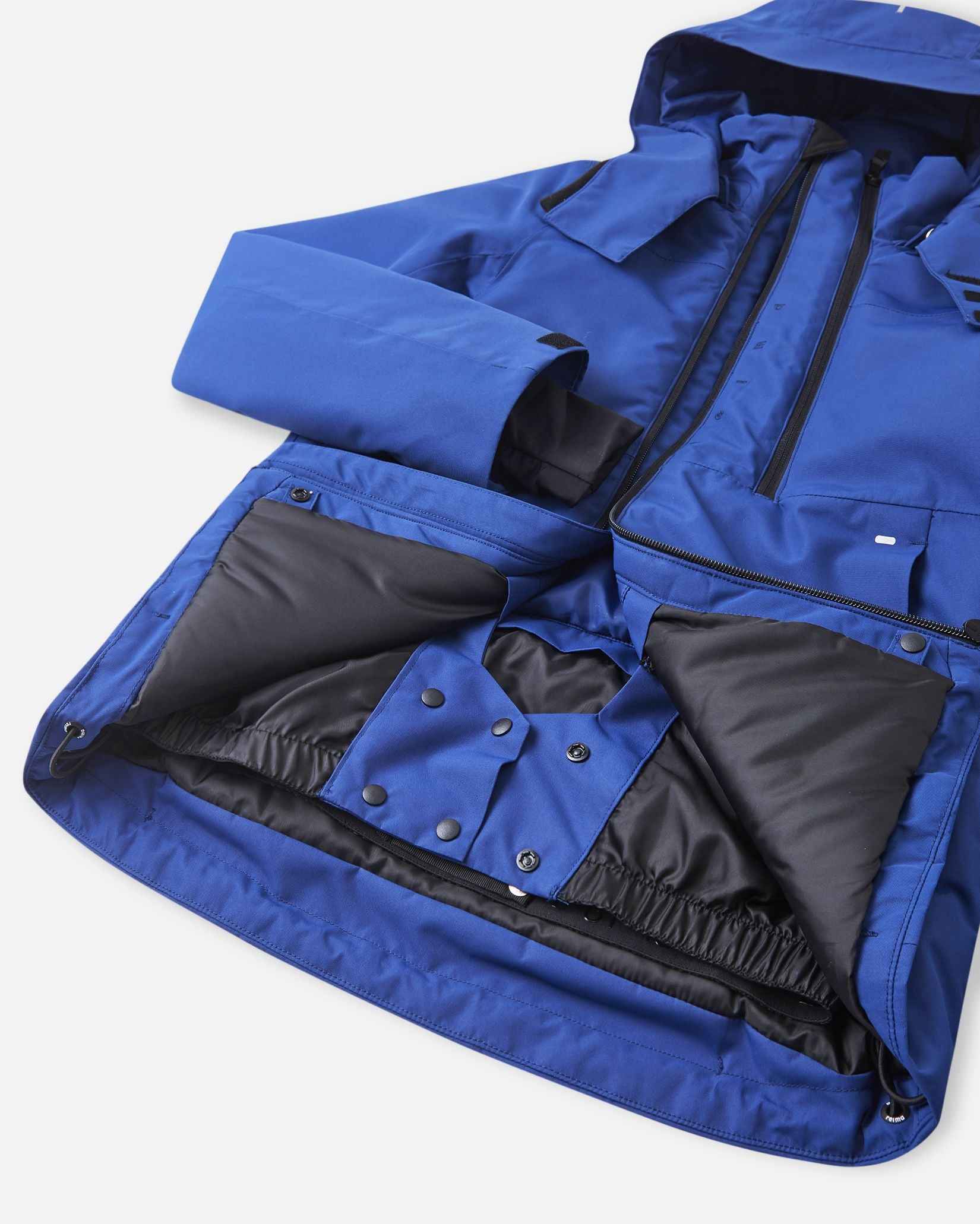 An open blue winter jacket displays an internal black zip pocket sitting next to a stretch mesh goggle pocket.