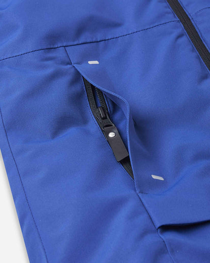 A black zipper opens slightly on the slanted side pocket of the blue kids snow jacket.