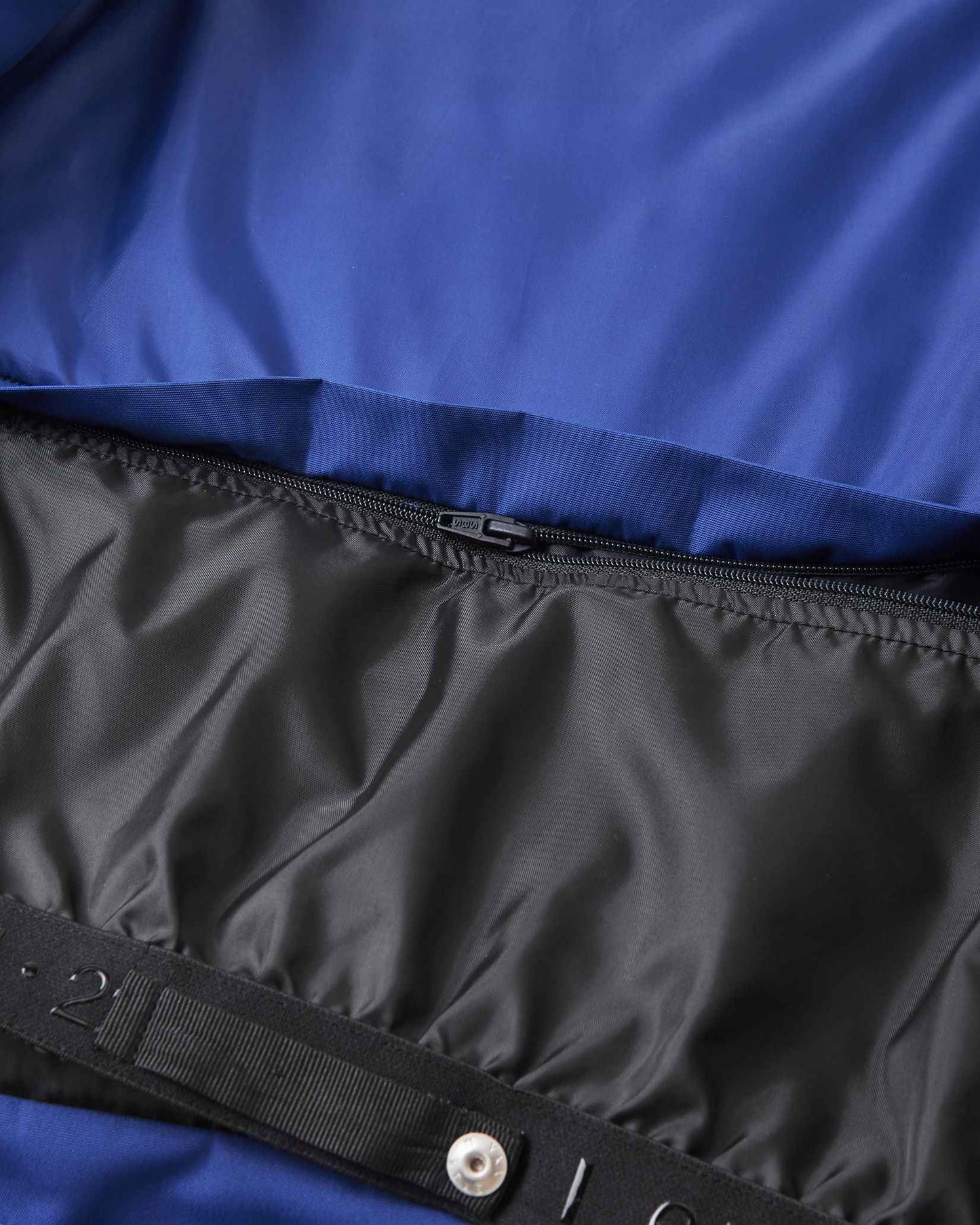 Metal snap buttons secure the black inner lining inside the blue Reima ski jacket.