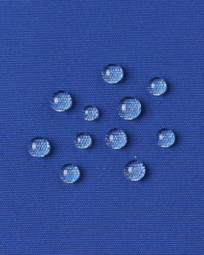 Water beads up on the twilight blue fabric of the Reima ski jacket to demonstrate its water resistance.