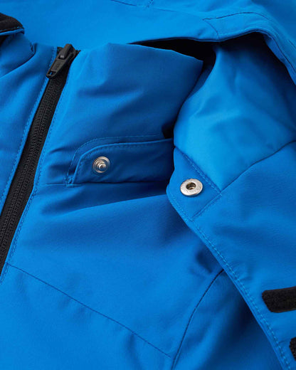 Detailed view of the tear-away metallic safety snaps along the neckline of the bright blue Reima Tieten youth winter jacket, designed to quickly release the hood if it gets caught on tree branches.