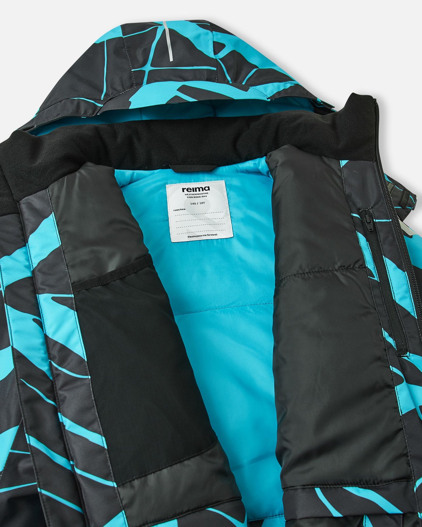 Inside view of the black Reima Tirro kids' waterproof ski jacket, showing the smooth blue winter lining, internal mesh goggle pocket, zippered chest pocket, and Reima name tag.
