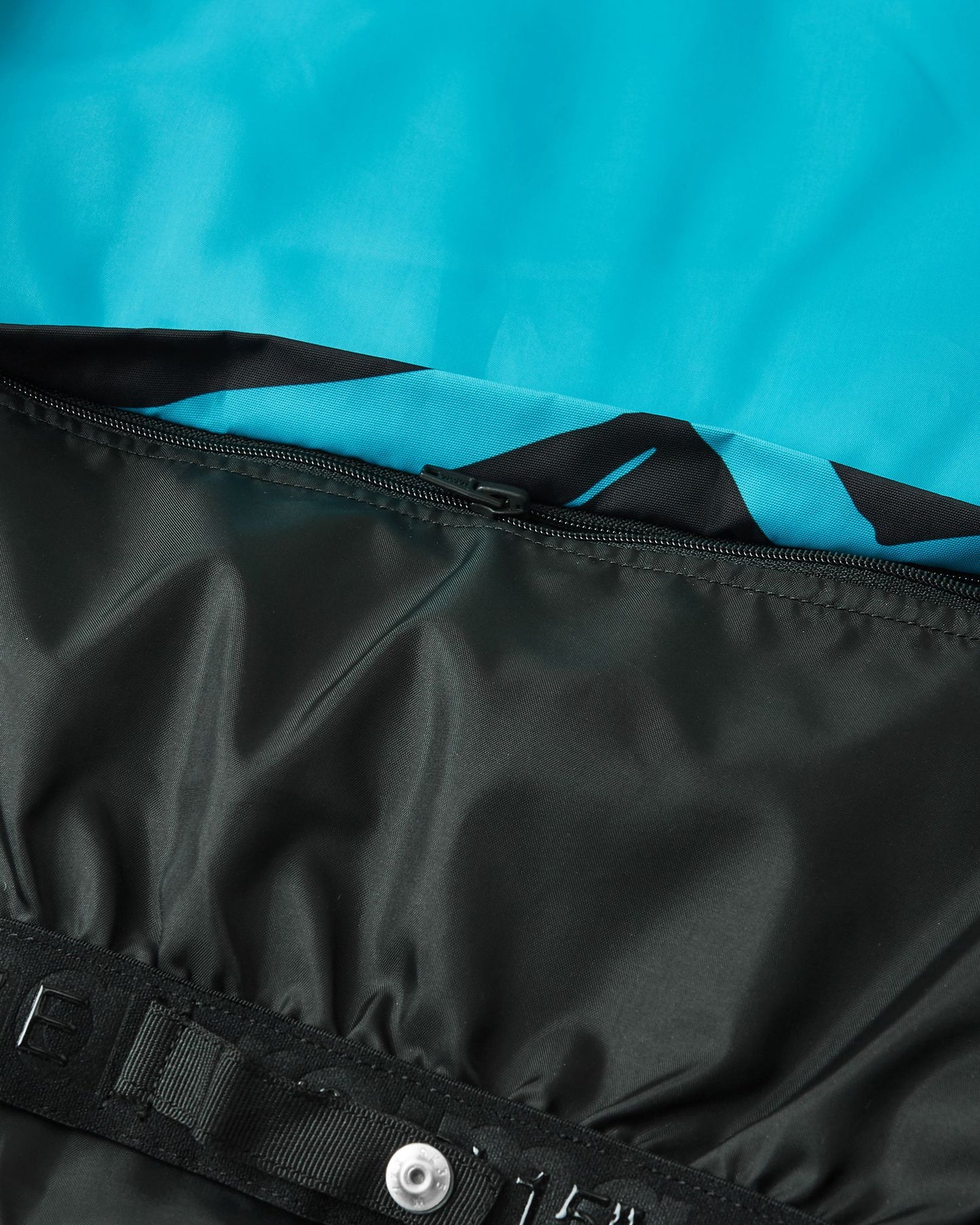 Close-up detail of the internal elastic snow powder skirt with secure snap buttons on the black Reima Tirro kids' winter ski jacket.
