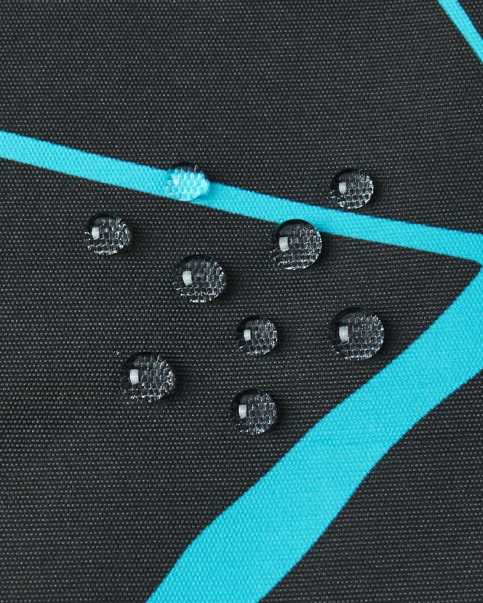 Macro close-up of water droplets perfectly beading on the surface of the black Reima Tirro kids' ski jacket, demonstrating the high-performance waterproof and breathable outer fabric.
