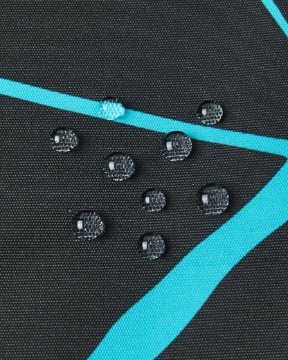 Macro close-up of water droplets perfectly beading on the surface of the black Reima Tirro kids' ski jacket, demonstrating the high-performance waterproof and breathable outer fabric.
