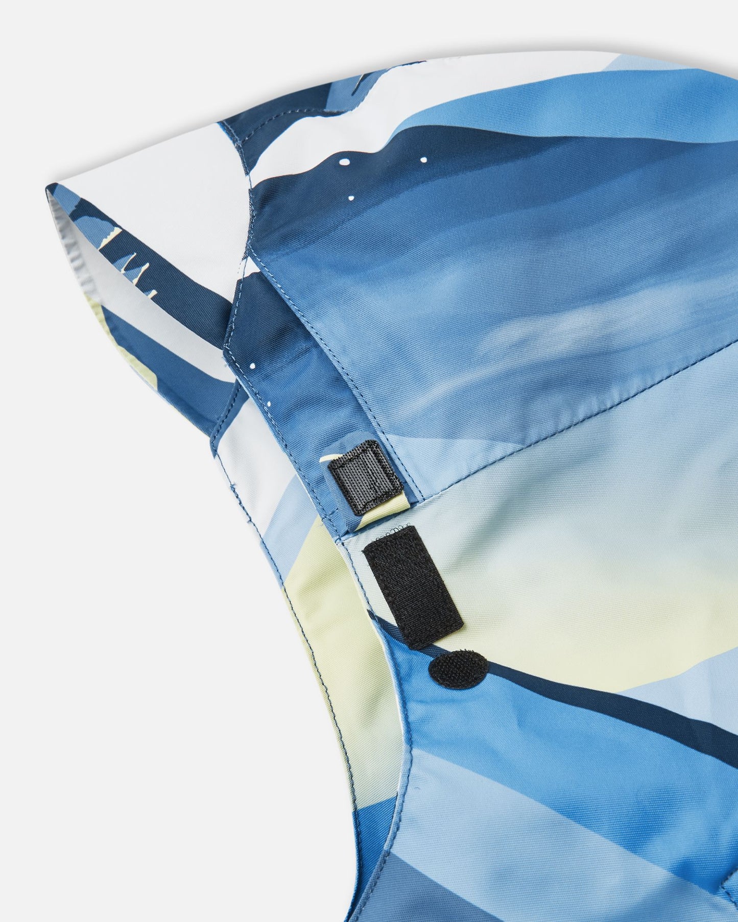 Detail view of the adjustable velcro collar flap on the Reima Tirro kids' ocean blue ski jacket, providing added wind and snow protection around the neck.