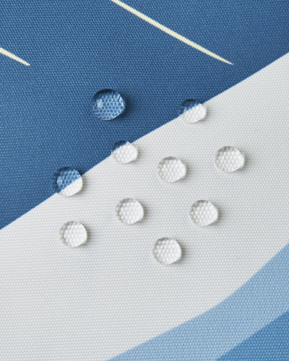 Macro close-up of water droplets beading on the surface of the Reima Tirro kids' ski jacket, demonstrating the high-performance waterproof and breathable ocean blue fabric.