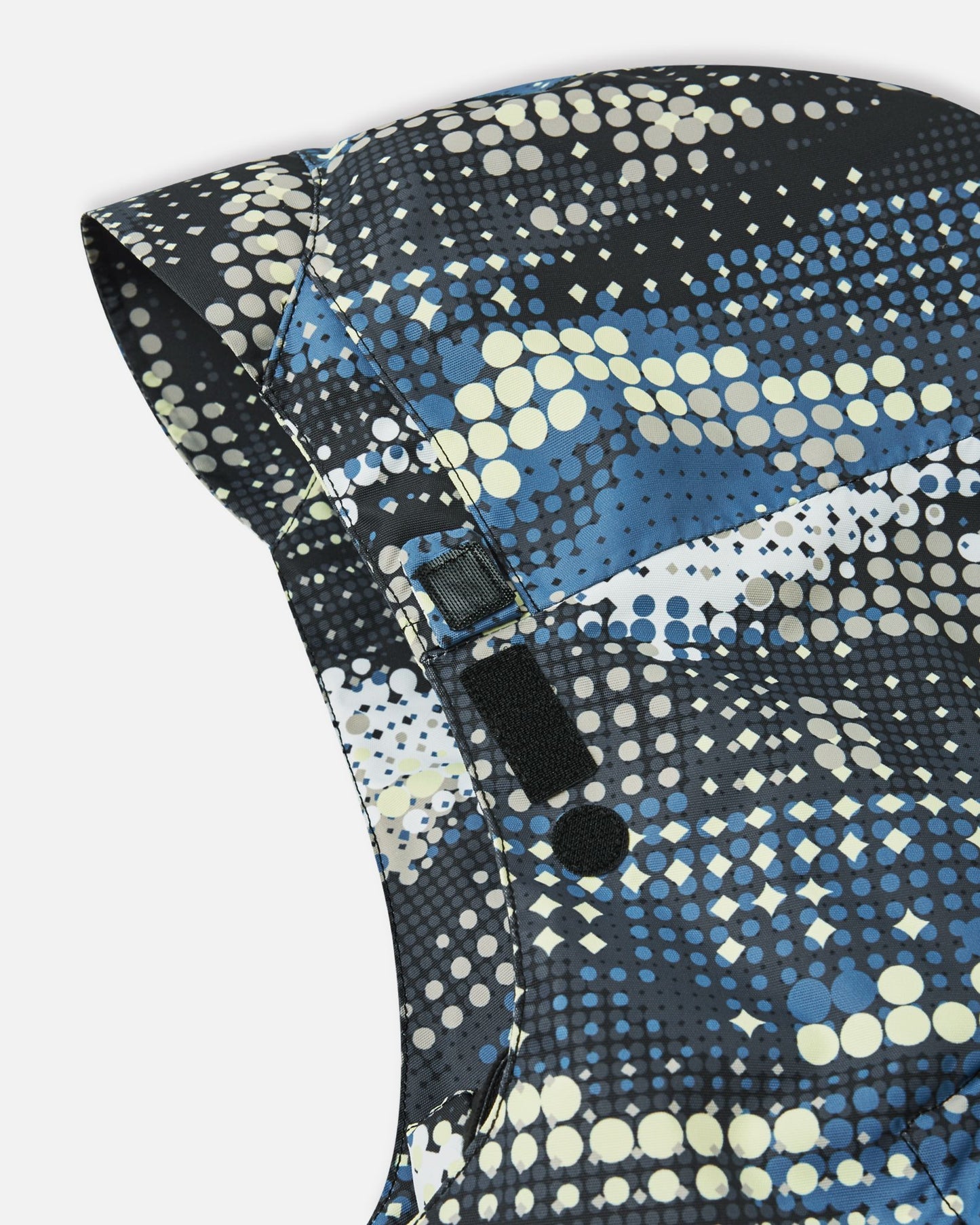 Detail view of the adjustable velcro strap on the hood of the soft black Reima Tirro kids' waterproof winter ski jacket, designed for a customized, secure fit over helmets.