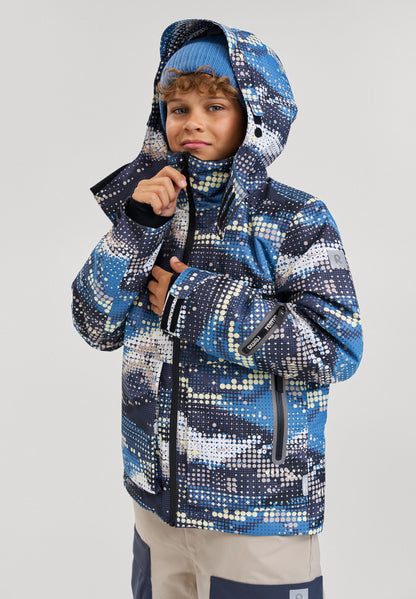 Lifestyle portrait of a young boy wearing the soft black Reima Tirro kids' waterproof ski jacket, adjusting the high collar for maximum cold weather protection during winter sports.