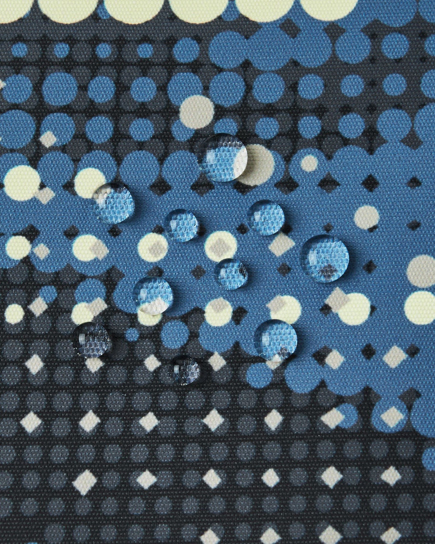 Macro close-up of water droplets perfectly beading on the surface of the soft black Reima Tirro kids' ski jacket, demonstrating the high-performance waterproof and breathable outer fabric.
