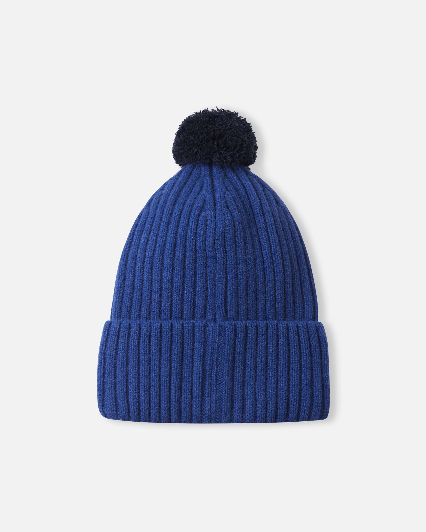 Back flat lay view of the twilight blue Reima Topsu kids' wool blend beanie, displaying the continuous stretchy ribbed knit pattern and the cozy navy pom-pom designed to retain heat on cold days.