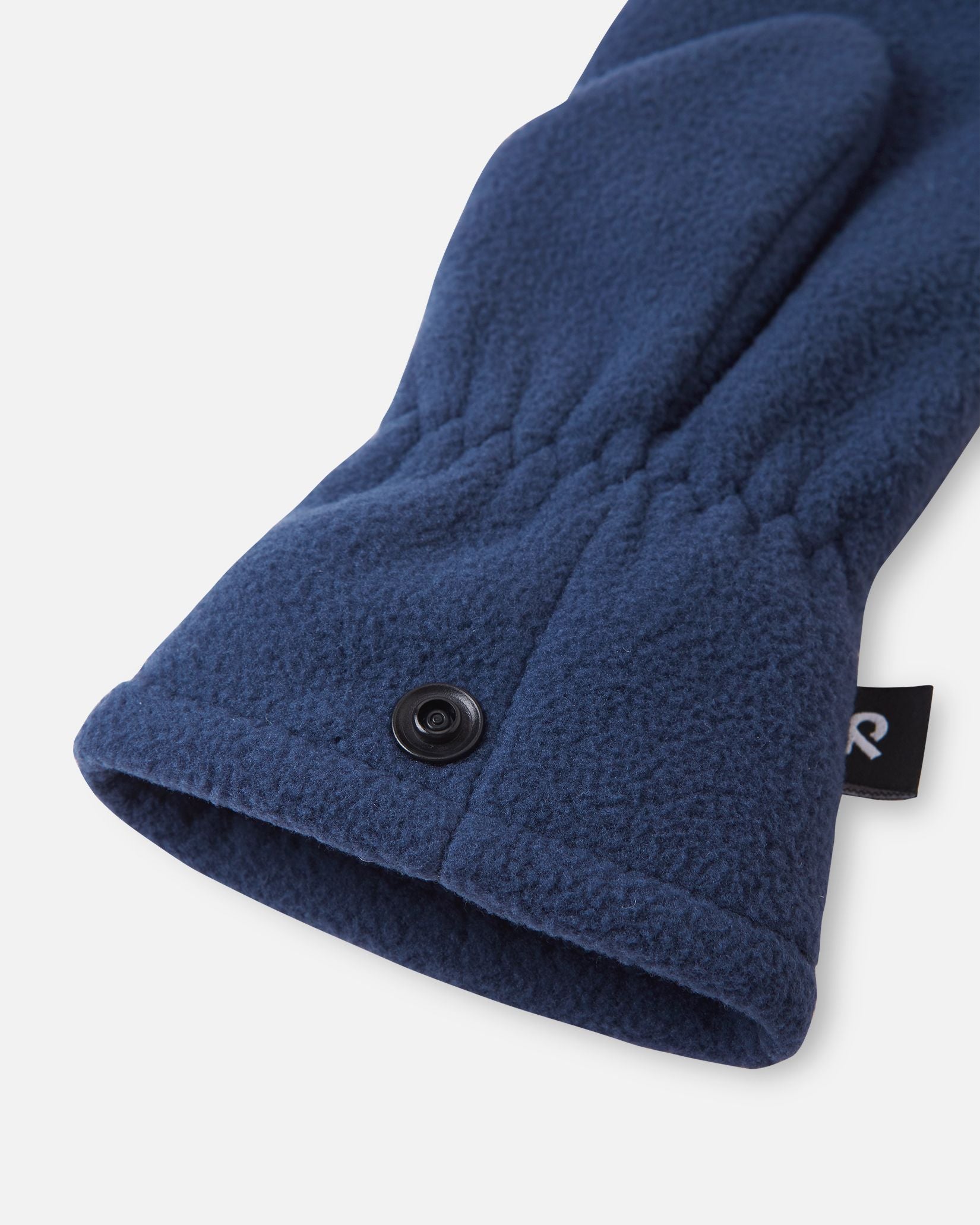 Detailed close-up of the gathered elastic wrist and snap button fastening system on the navy blue Reima Tumpus kids' cozy fleece mitten.