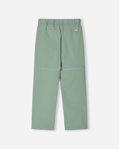 Back view of the stone green Reima Tuplat kids' hiking pants, showcasing the durable, stretch outdoor fabric, clean back profile, and a reflective safety detail on the lower right leg for trail visibility.