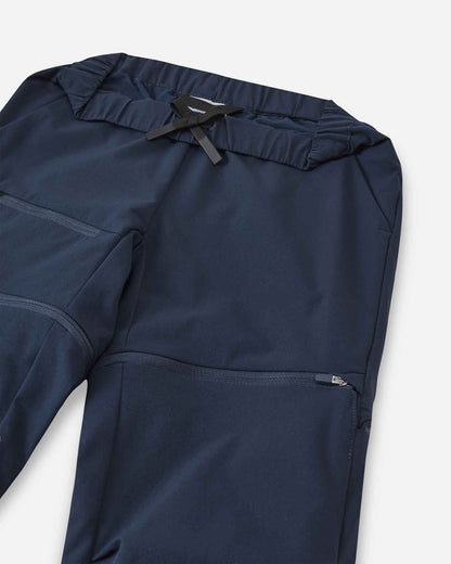 Detailed close-up of the upper section of the Reima Tuplat kids' navy blue convertible pants, showcasing the adjustable black inner drawstring, elastic waistband, and the smooth zip-off attachment for the lower legs.