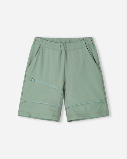 Front view of the Reima Tuplat kids' hiking pants converted into stone green shorts, highlighting the versatile zip-off design, relaxed fit, and practical zippered cargo pocket for warm weather hiking.