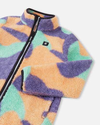 Close-up of the upper section of the apricot Reima Tupsis kids' teddy fleece, detailing the reliable full zipper, cozy collar, bound cuffs, and the signature Reima chest logo.