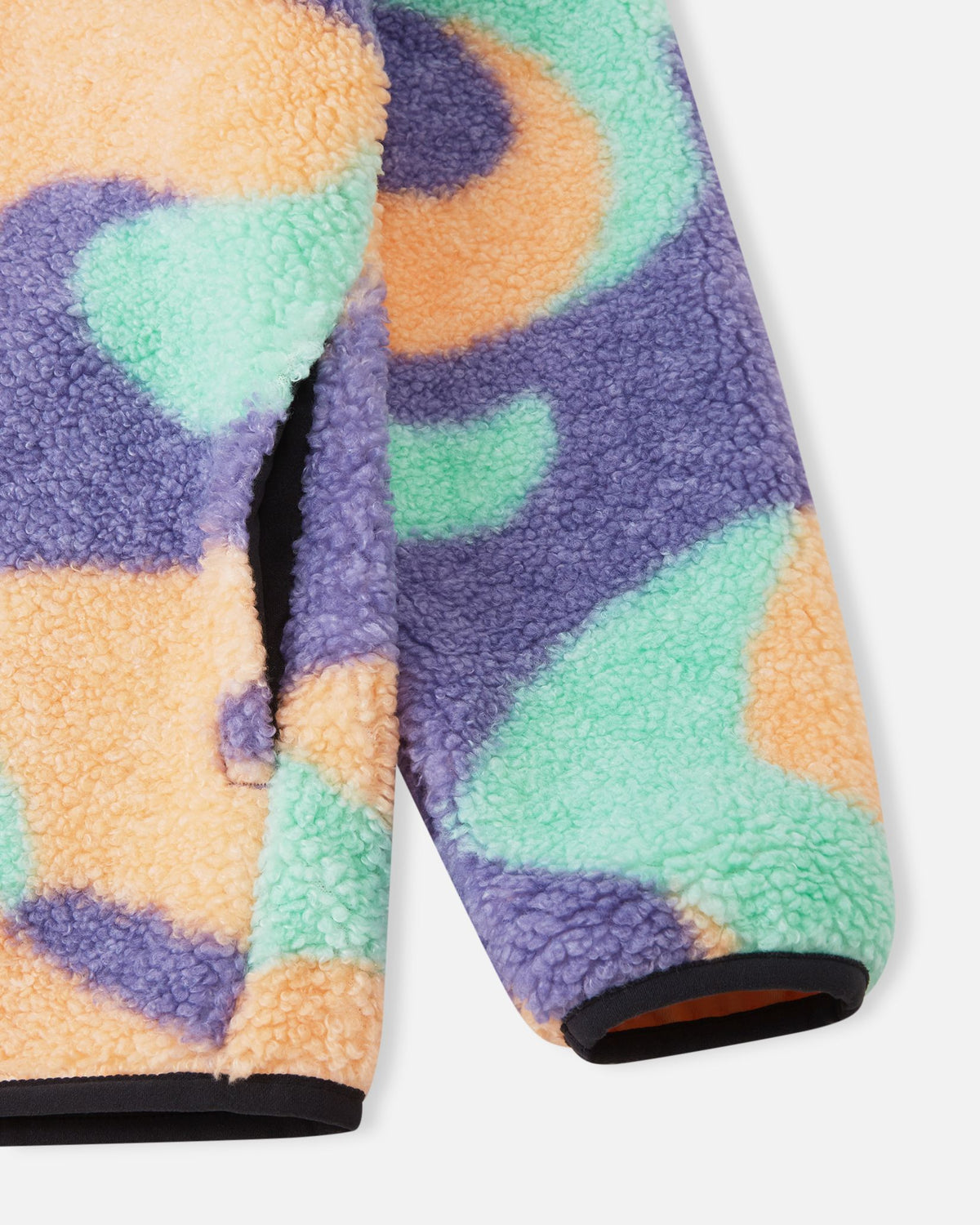 Detailed close-up of the apricot Reima Tupsis fleece jacket, focusing on the thick, warm teddy texture, the cleanly finished elastic cuffs, and the accessible side pocket.