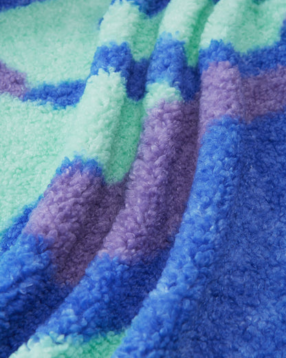 Macro close-up of the ultra-soft, thick teddy fur fleece used on the sparkly blue Reima Tupsis kids' jacket, showing the rich texture and vibrant colors of the camo pattern.