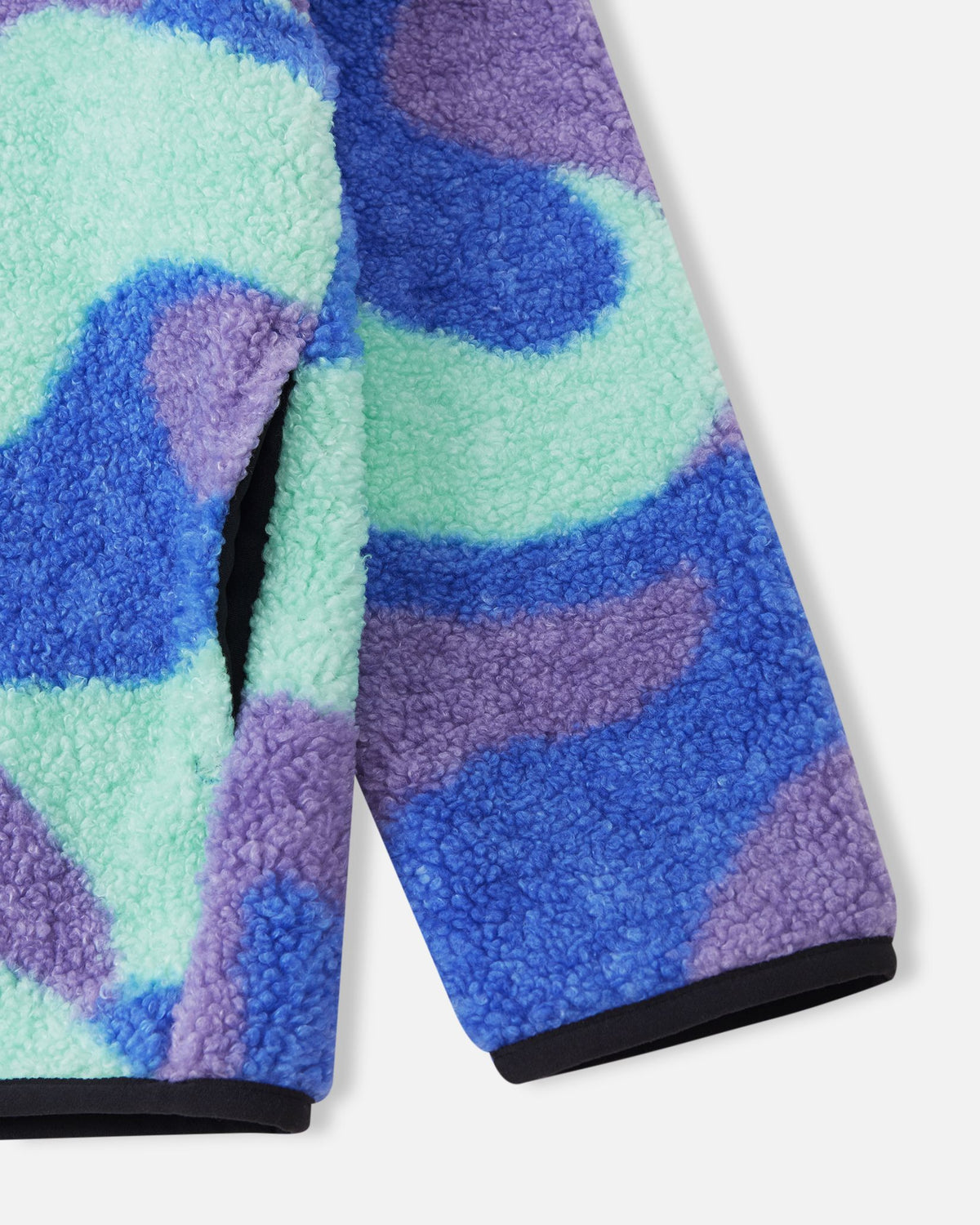 Detailed close-up of the sparkly blue Reima Tupsis fleece, focusing on the comfortable elastic cuffs with black binding, the soft teddy fur texture, and the convenient side pocket.