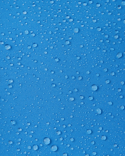 Macro close-up of water droplets beading and rolling off the surface of the Reima Vantti kids' cool blue softshell jacket, demonstrating the highly waterproof and dirt-repellent material.