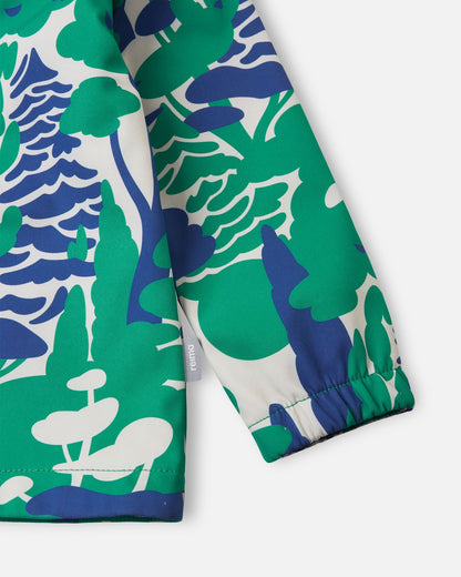 Detailed close-up of the sleeve on the green Reima Vantti kids' softshell jacket, highlighting the bold forest print, the small Reima logo tag, and the snug elastic cuff that seals out wind.