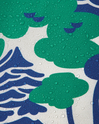 Macro close-up of water droplets beading and rolling off the surface of the Reima Vantti kids' green forest print softshell jacket, demonstrating the highly waterproof and dirt-repellent material.