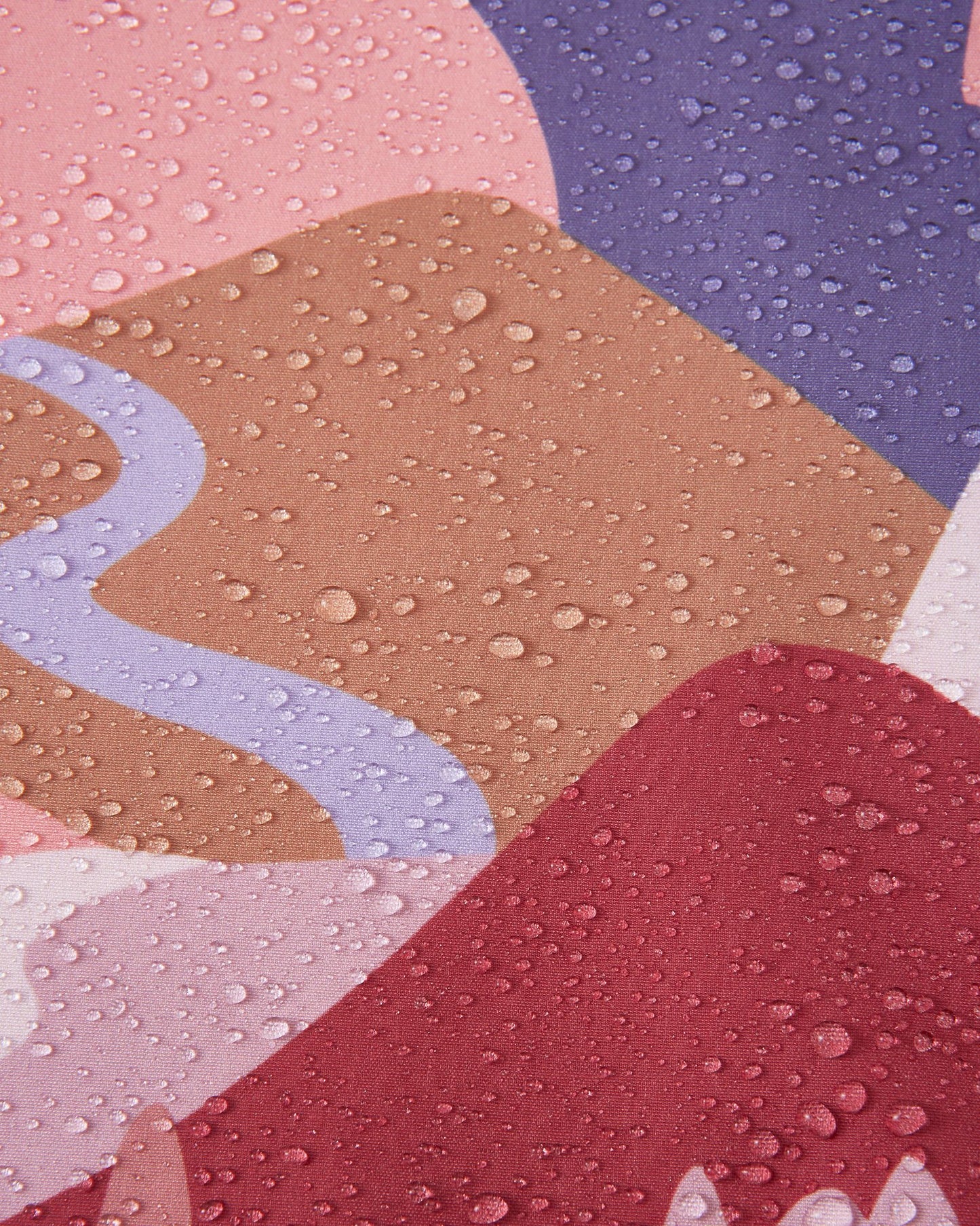 Macro close-up of water droplets beading up and rolling off the surface of the Reima Vantti kids' rose blush softshell jacket, demonstrating the highly waterproof and dirt-repellent material.
