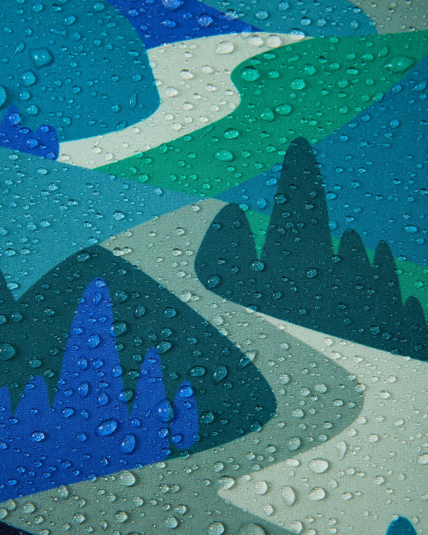 Macro close-up of water droplets beading up and rolling off the surface of the Reima Vantti kids' sparkly blue softshell jacket, demonstrating the highly waterproof and dirt-repellent material.