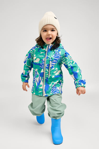 Lifestyle shot of an active toddler wearing the green forest print Reima Vantti kids' softshell jacket paired with light green rain pants and blue boots, demonstrating its comfortable and protective fit for rainy day play.