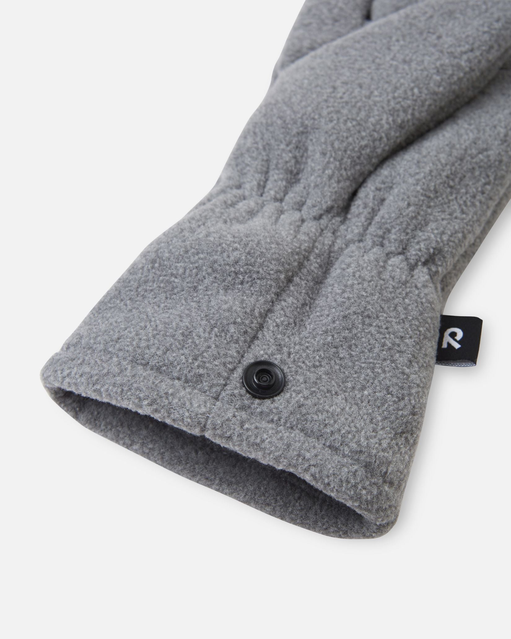 Close-up detail shot of the Reima Varmin kids' fleece gloves in melange grey, highlighting the warm fleece fabric, the gathered elastic wristband, and the practical black snap button fastener used to clip the pair together so they don't get separated.