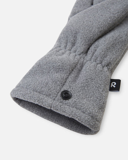 Close-up detail shot of the Reima Varmin kids' fleece gloves in melange grey, highlighting the warm fleece fabric, the gathered elastic wristband, and the practical black snap button fastener used to clip the pair together so they don't get separated.