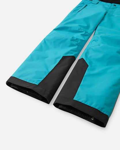 Detail view of the lower legs on the aquatic Reima Wingon kids' ski pants, emphasizing the rugged black reinforced hems to protect against ski edges and the inner elastic snow locks designed to securely grip winter boots.