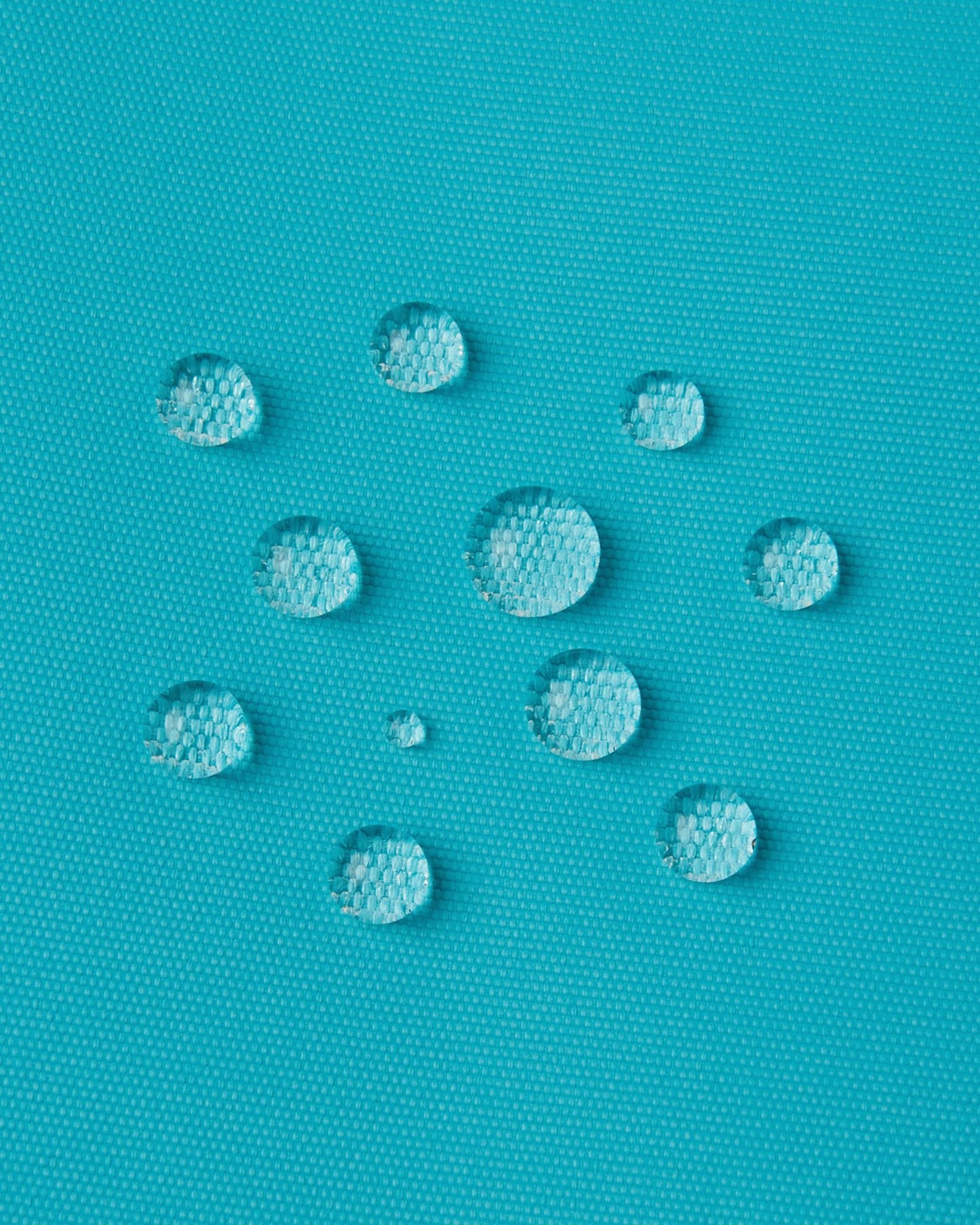 Macro close-up of water droplets actively beading and rolling off the aquatic outer shell of the Reima Wingon kids' ski pants, visually highlighting the high-performance breathable and waterproof Reimatec technology.