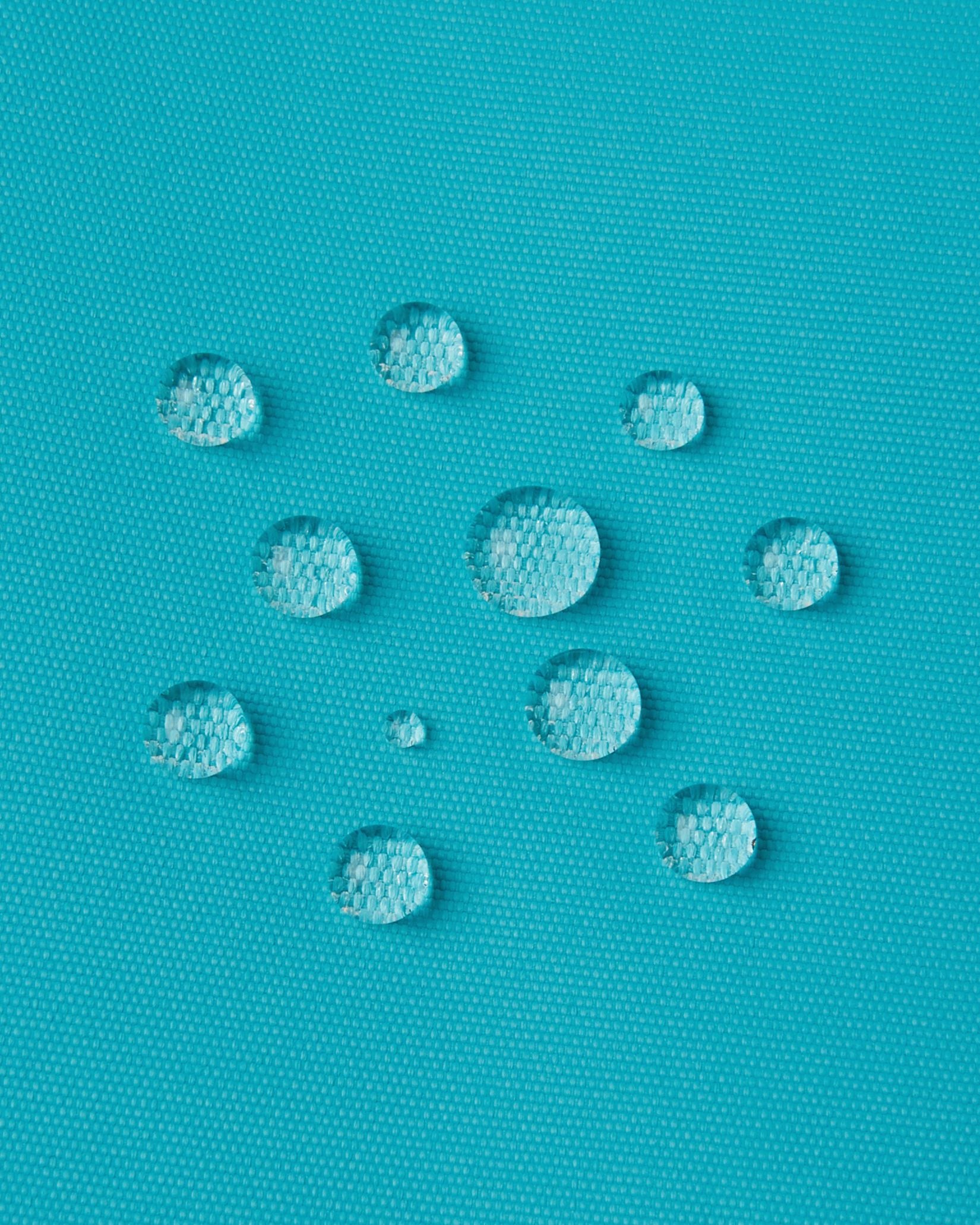 Macro close-up of water droplets actively beading and rolling off the aquatic outer shell of the Reima Wingon kids' ski pants, visually highlighting the high-performance breathable and waterproof Reimatec technology.