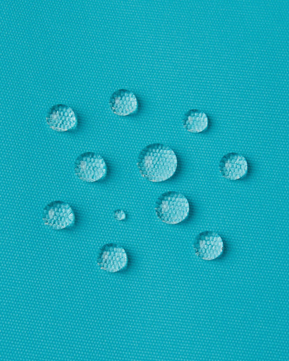 Macro close-up of water droplets actively beading and rolling off the aquatic outer shell of the Reima Wingon kids' ski pants, visually highlighting the high-performance breathable and waterproof Reimatec technology.