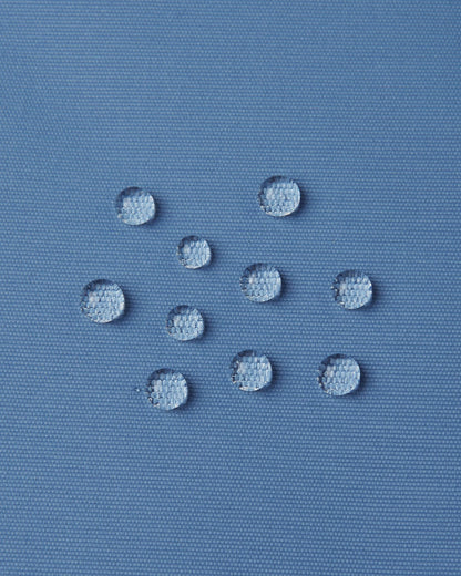 Macro close-up of water droplets actively beading and rolling off the blue ocean outer shell of the Reima Wingon kids' ski pants, visually highlighting the high-performance breathable and waterproof Reimatec technology.